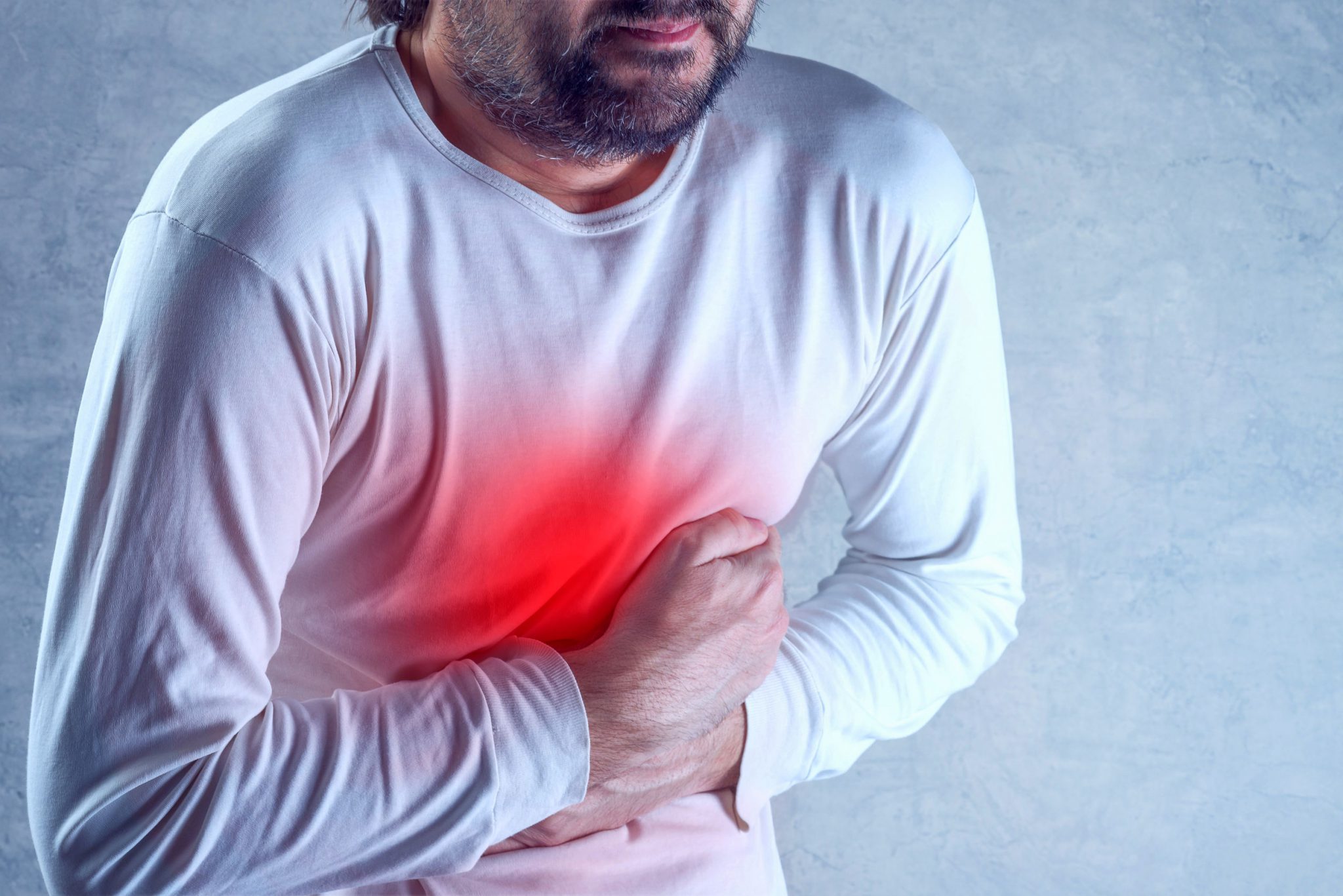 Man suffering from severe abdominal pain, hands on stomach